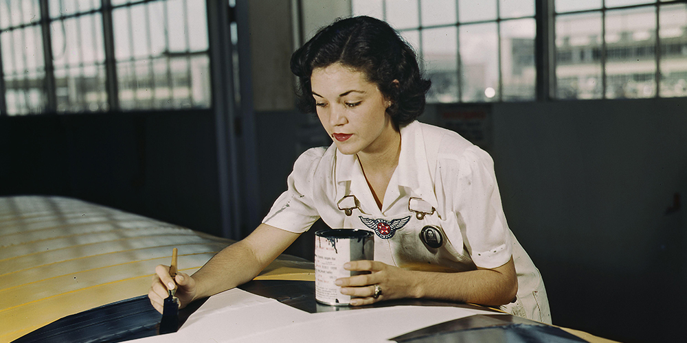 Woman paints the USAF insignia star on a plane wing