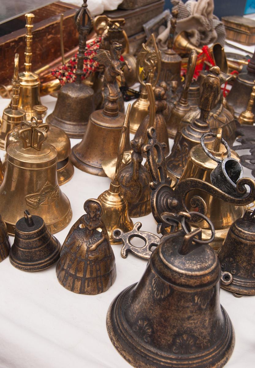 Assorted handheld bells on display at an open-air antique market